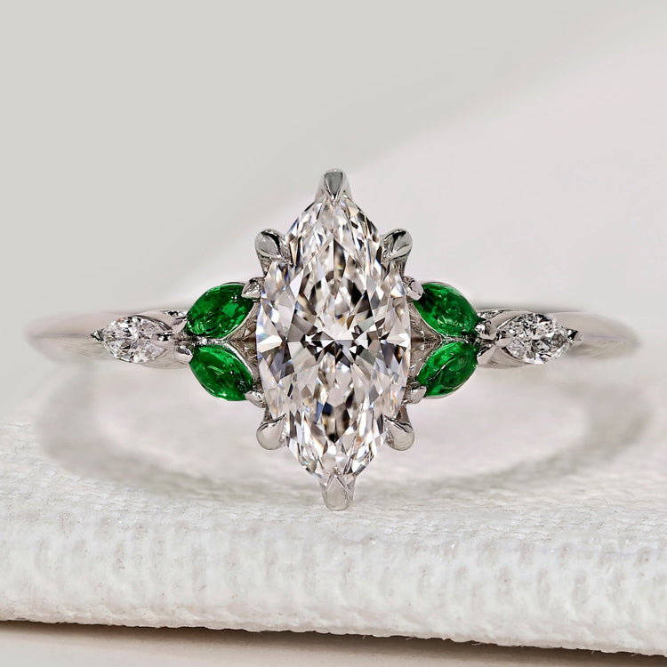 Marquise ring with dark green emerald side stones.
