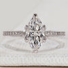 Marquise engagement ring with round diamond pavé.
