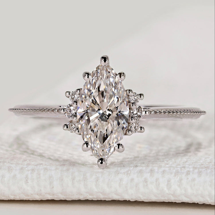 Marquise ring with round side stones and milgrain.
