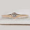 Minimalist round diamond ring with bezel setting.

