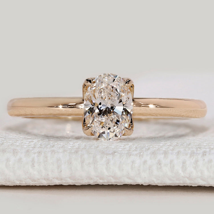 Oval diamond ring with hidden halo and round diamonds.
