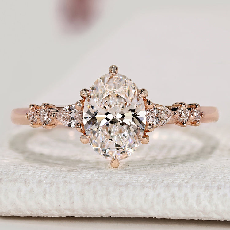 Oval diamond ring with pear and round side stones.
