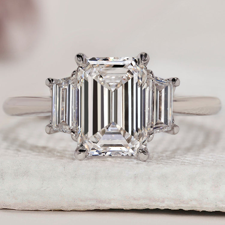 3 stone ring with emerald cut centre and trapezoid side stones.
