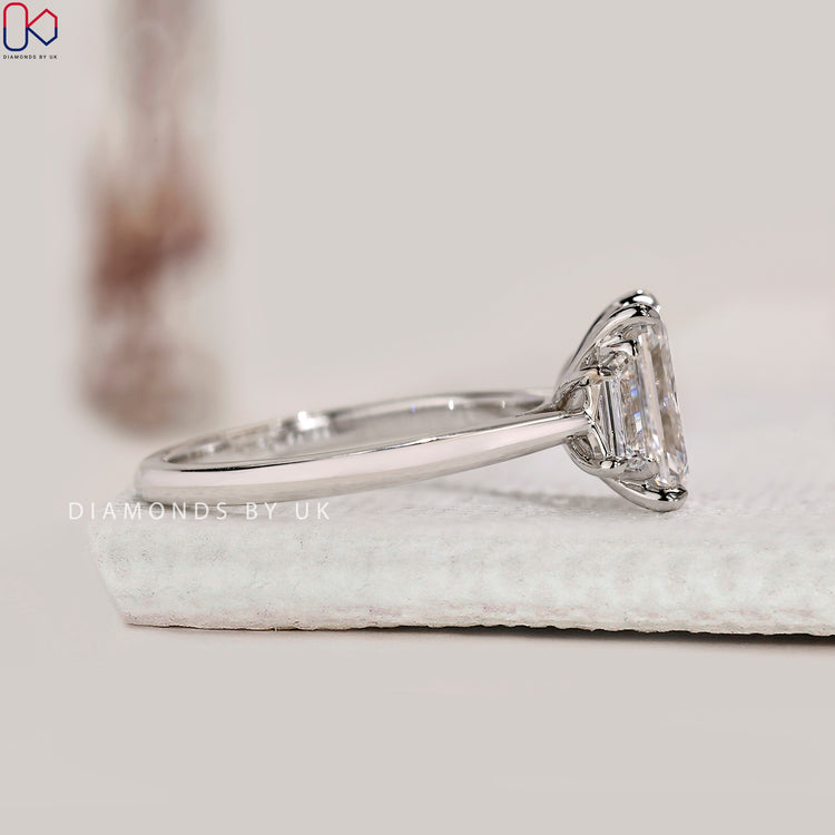 4 prong claw setting holding emerald cut centre stone.

