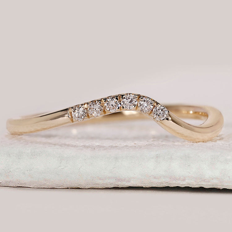Curved diamond wedding band in yellow gold.
