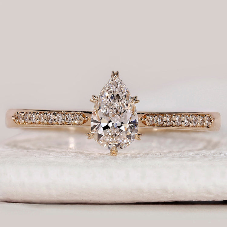 Pear cut engagement ring with tapered pavé band.
