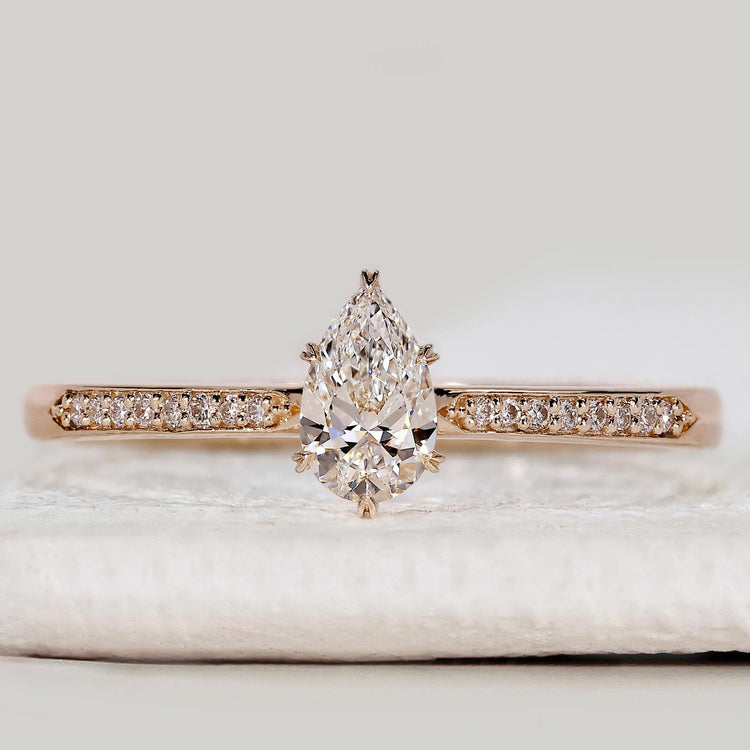 Pear cut engagement ring with tapered pavé band.
