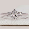 Pear diamond ring with three stone round side design.