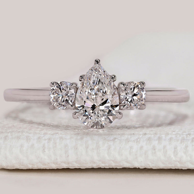 Pear diamond ring with three stone round side design.