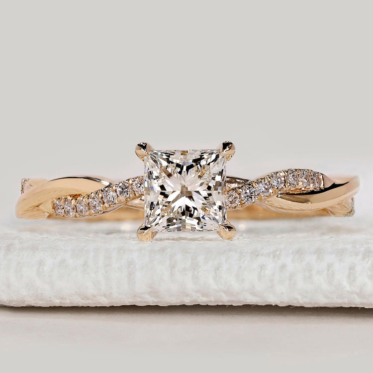 Princess cut ring with twisted pavé diamond band.