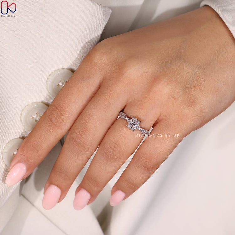 IGI Certified Cushion Cut Diamond Ring with round side diamonds, set in a twisted pave band crafted in white gold.

