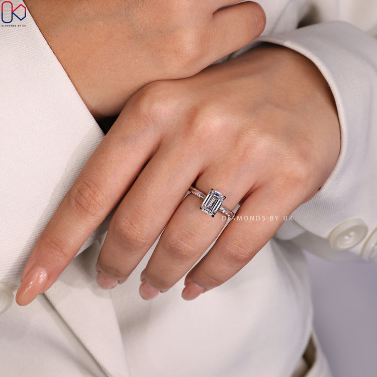 Diamondsbyuk Engagement Ring with an Emerald Cut Diamond and side diamonds, crafted in white gold for a perfect proposal.