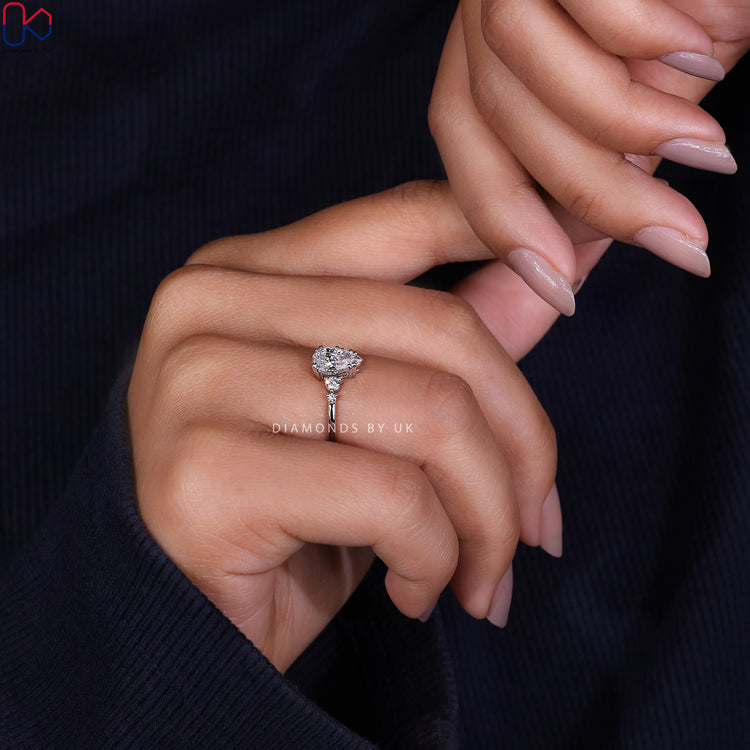 Diamondsbyuk Ring with a pear diamond and round side stones for a modern look.

