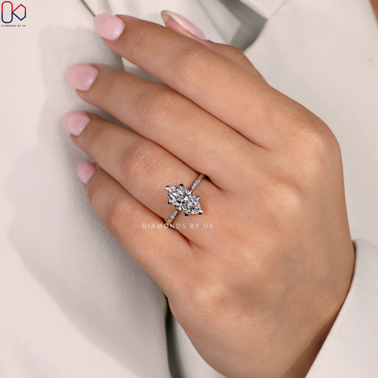 IGI Certified Marquise Diamond Ring with round side diamonds, set in a tapered shank band and crafted in white gold.
