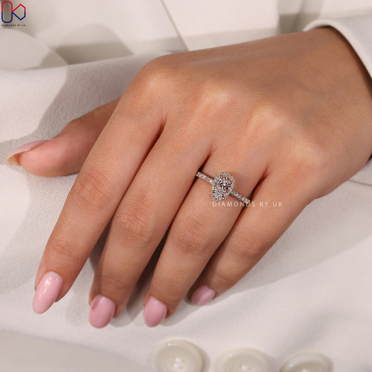 Engagement ring UK with a pear shaped diamond and halo diamond ring accents.
