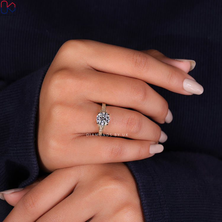 Bridge accent engagement ring with a round brilliant cut diamond ring centrepiece.
