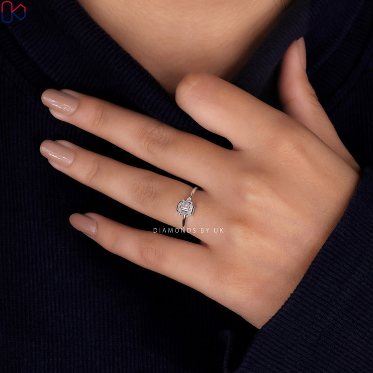 Bezel setting ring with round and emerald cut diamonds for elegance.