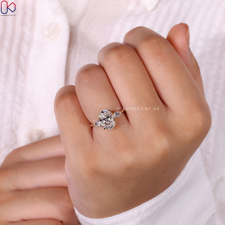 Oval ring with pear-shaped side stones in a luxurious setting.
