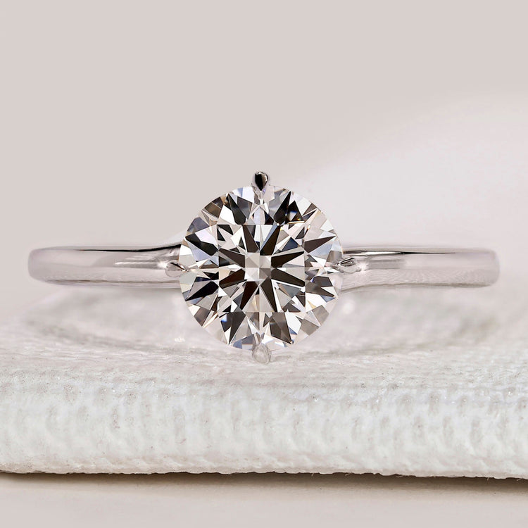 Round cut solitaire ring with four claw compass prongs.
