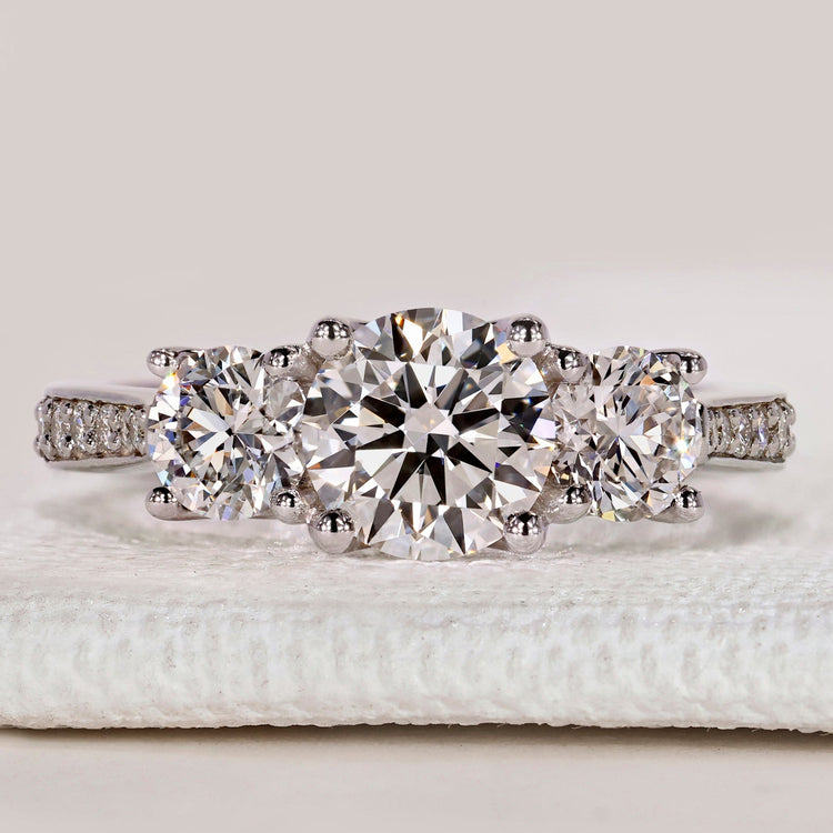 Round cut three stone ring with pavé tapered shank.
