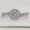 Round cut engagement ring with halo and twisted pavé.
