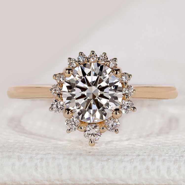 Round diamond ring with cluster halo and four prongs.
