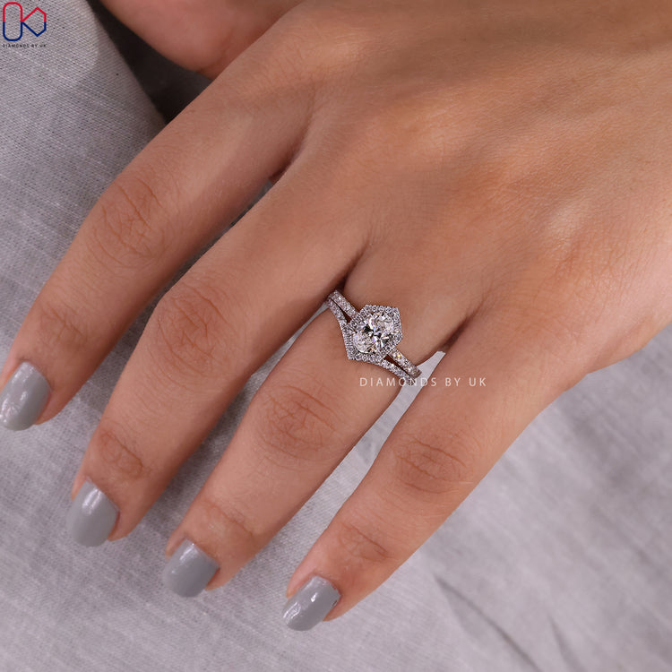 Halo engagement ring with oval diamond and curved diamond band.
