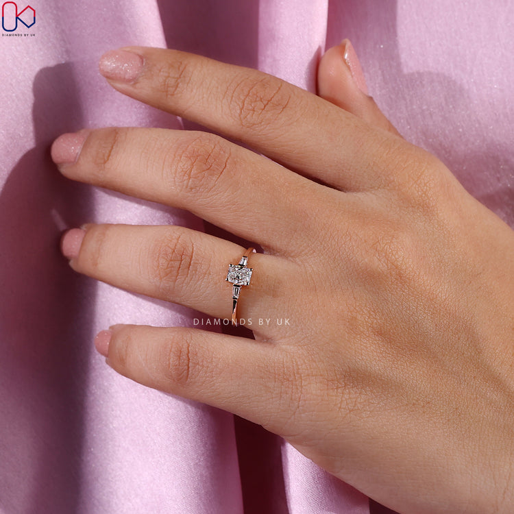 Side stone engagement ring featuring a radiant cut diamond.
