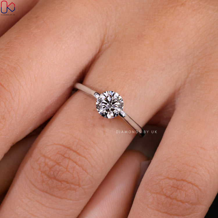 Diamondsbyuk round solitaire engagement ring with a white gold band.
