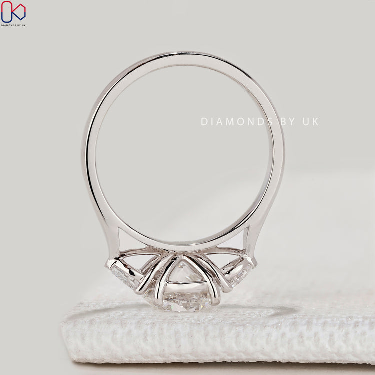 Round cut three stone ring with pear side diamonds.