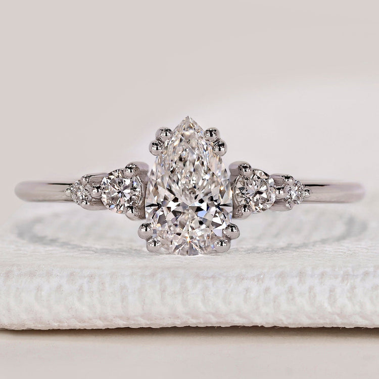 Pear cut ring with round side stones and muse setting.