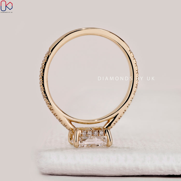 East to west radiant cut ring with pavé diamonds.