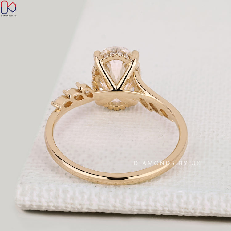 Oval engagement ring with cathedral setting and halo.
