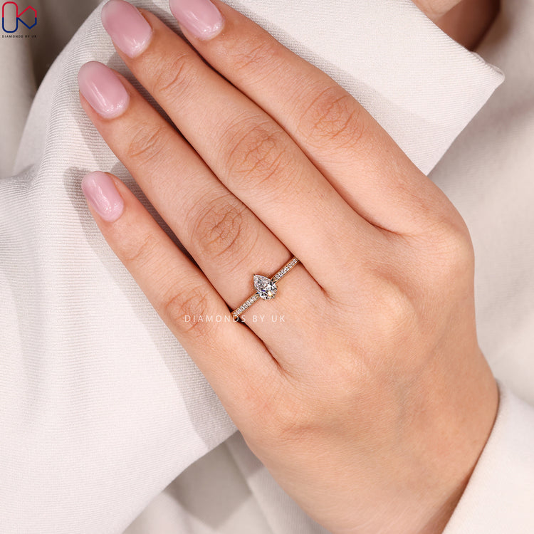 Pear cut engagement ring with pavé diamond band.