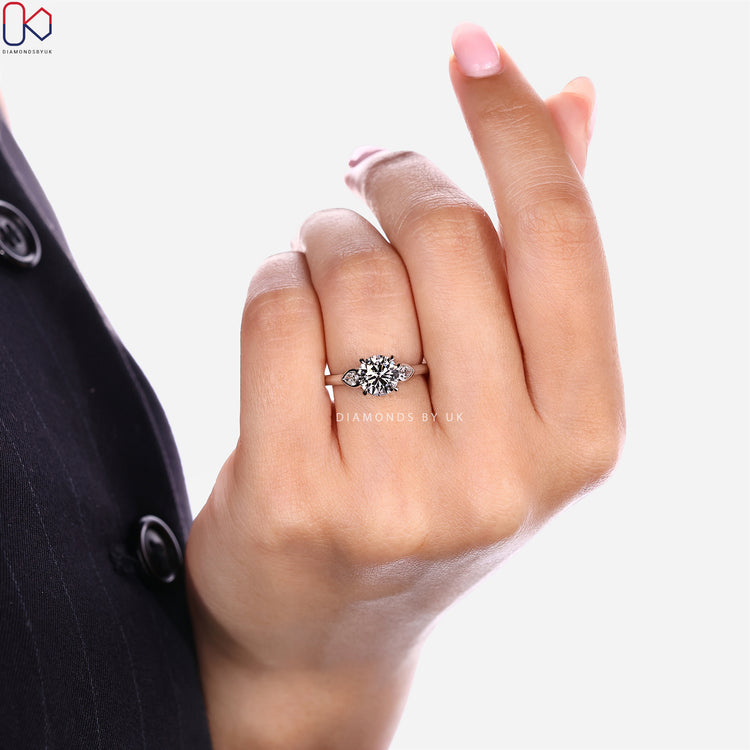 Round cut diamond ring with round diamond bridge accents.
