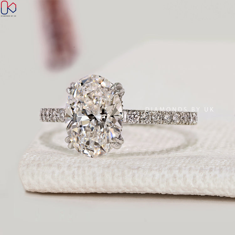 Oval diamond ring with round diamond pavé and halo.
