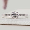 Round cut engagement ring with pavé and claw prong setting.