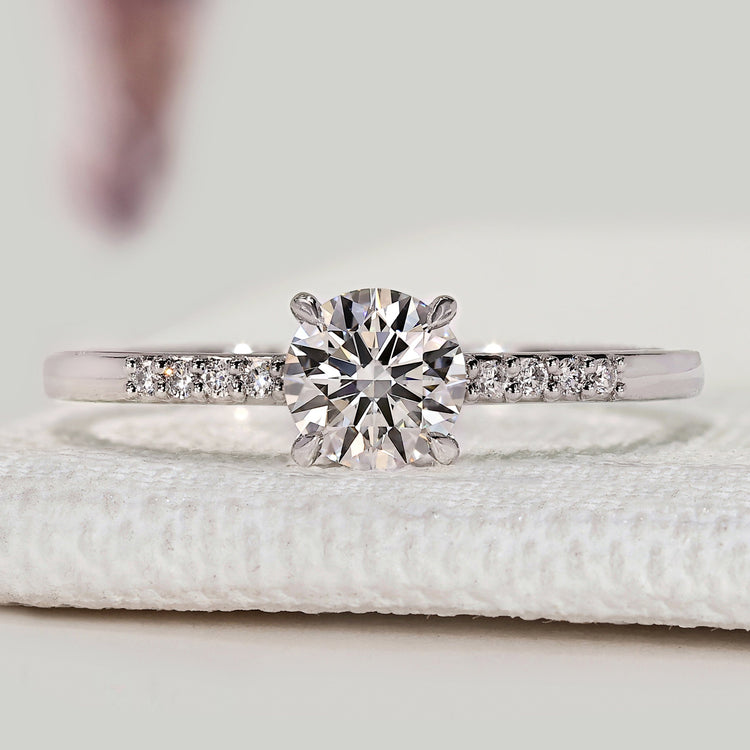 Round cut engagement ring with pavé and claw prong setting.