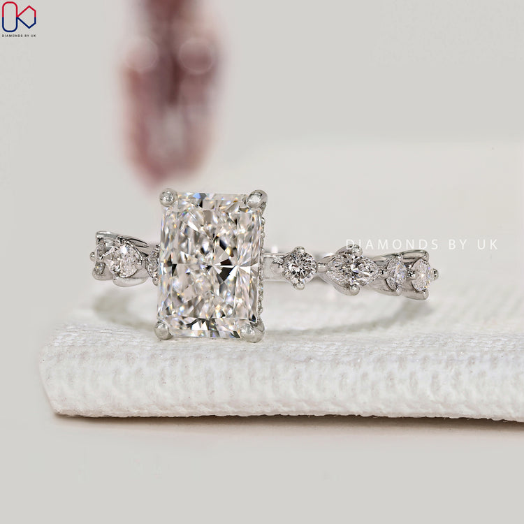 Radiant diamond ring with round and marquise side stones.
