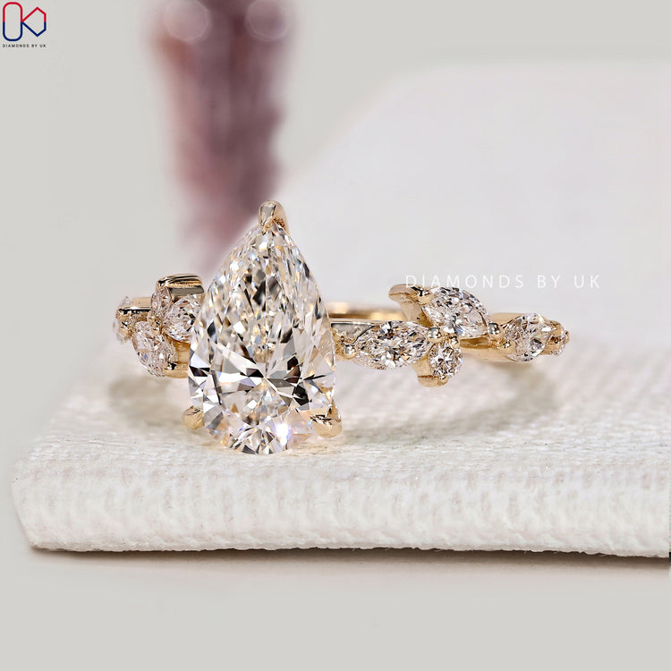 Pear diamond ring with marquise side stones and prongs.