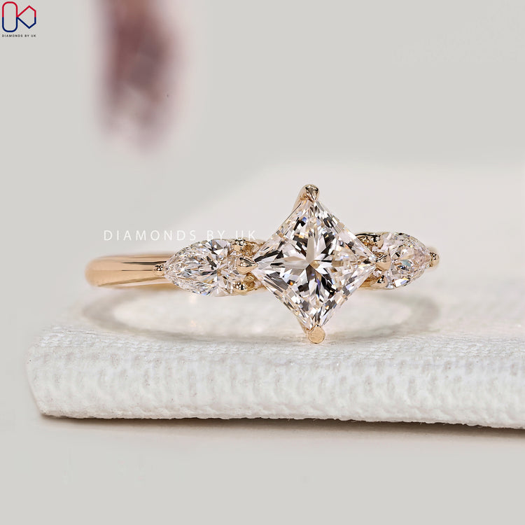 Princess cut ring with pear side stone and compass prongs.
