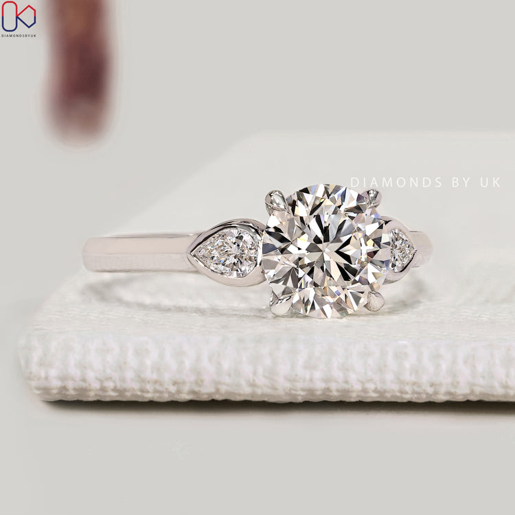 Three stone round diamond ring with pear side stones.
