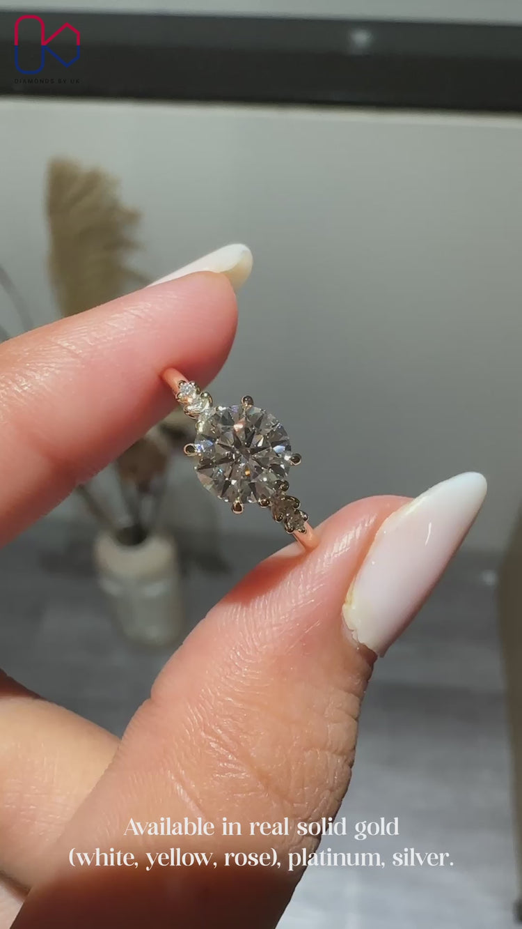 Round cut ring with side stones and prongs.