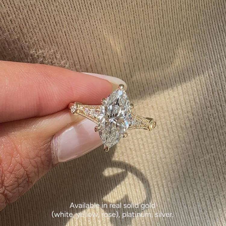 Marquise engagement ring with round diamond and split shank.
