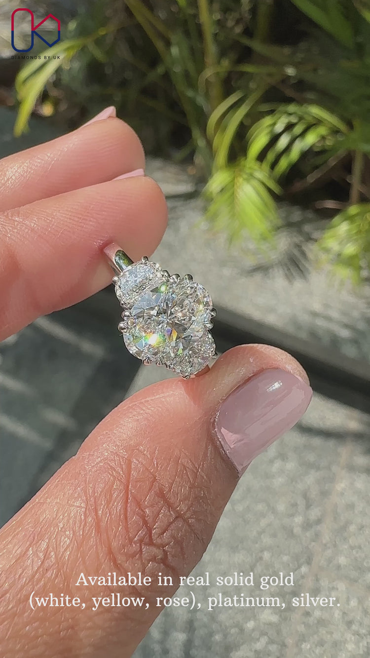 3 stone engagement ring featuring oval center diamond.
