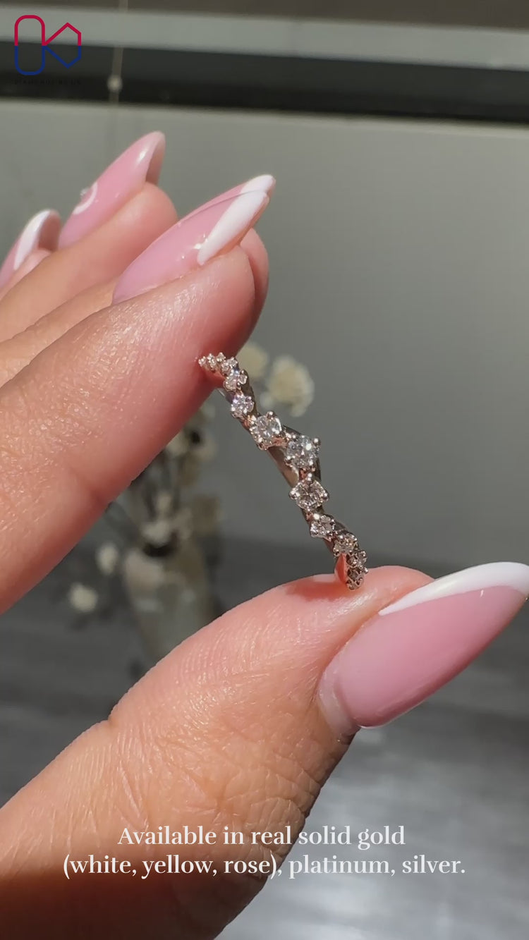 Curved wedding band featuring round cut diamonds in a prong setting.
