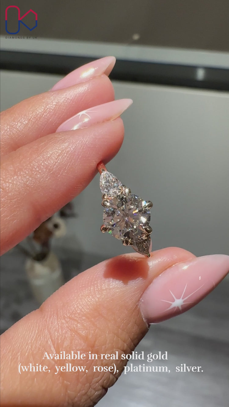 Round diamond ring with pear side stones set in a beautiful design for added elegance.
