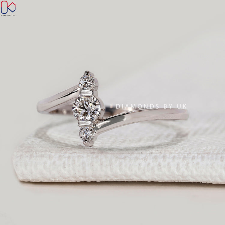Round diamond three stone ring with vertical bar.
